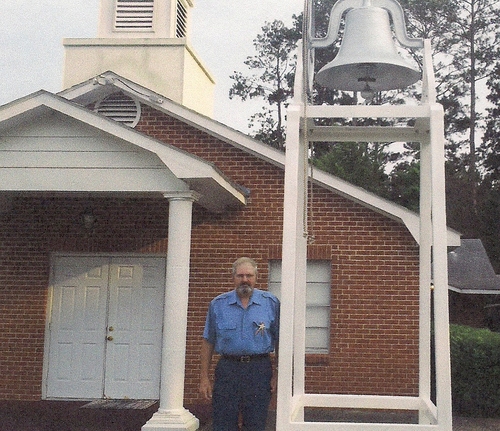 Rickey Robertson standing by the church bell at Pine Grove Baptist Church.