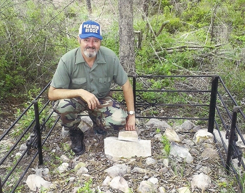 Rickey Robertson kneels at the grave of L.C. Curby, the man who killed the last buffalo in Louisiana. Grave is located in the Kisatchie National Forest.