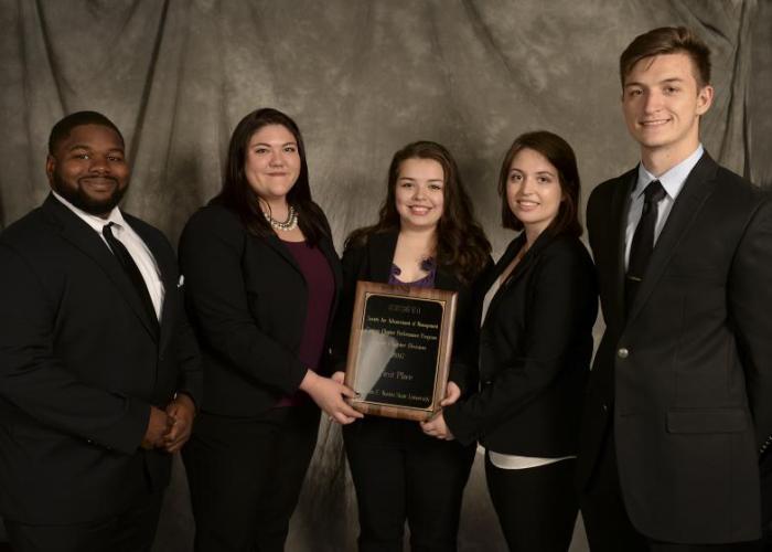 students pose with an award