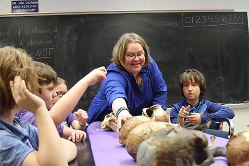 Dr. Karol Chandler-Ezell and fourth graders from the SFA Charter School participate in a hands-on activity in the SFA anthropology lab. 