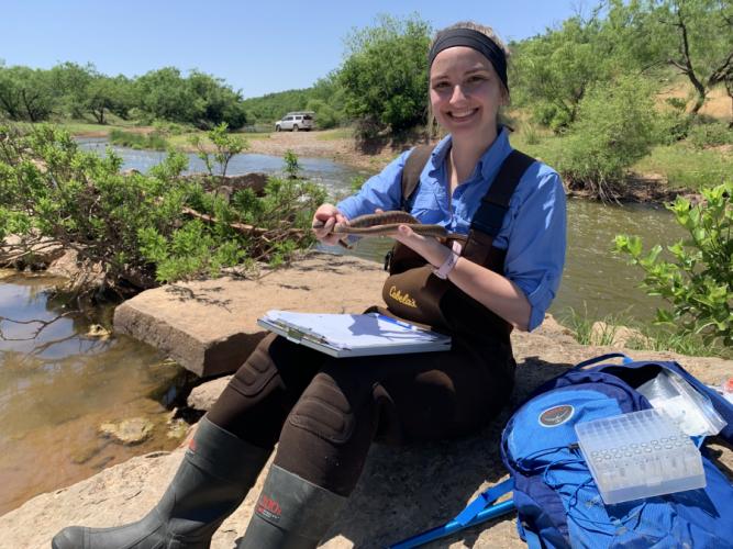 SFA biology graduate student Jessie Johnson in the field holding a watersnake