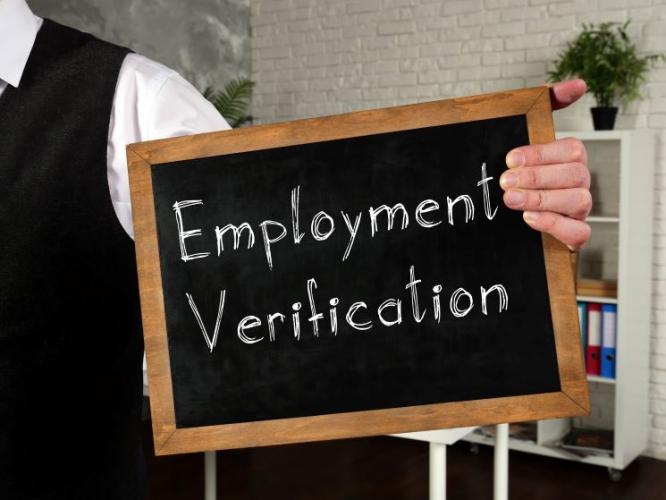 person holding a chalkboard sign reading "Employment Verification"