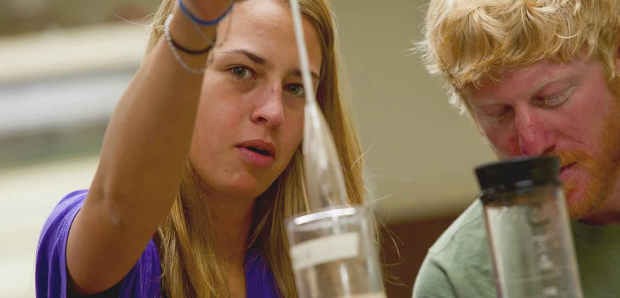 Two SFA students analyze a liquid sample in a lab