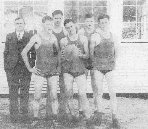 Bobbie Robertson, holding basketball, captain of the Plainview High School basketball team 1942. The team played their games on a dirt court.