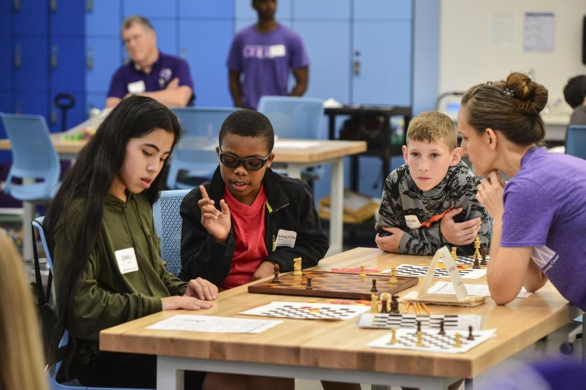 SFA alumna Rachel Payne helps students play a game based on chess.