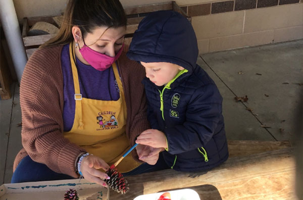Child painting with teacher assistant