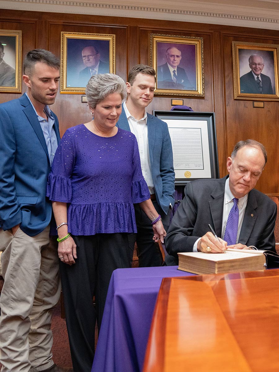 Dr. Steve Westbrook signs the Bible all previous SFA presidents signed before him while surrounded by his family: wife, Dayna, and sons, from left to right, Reed and Bryce. Photo by Lizeth Rodriguez Santes
