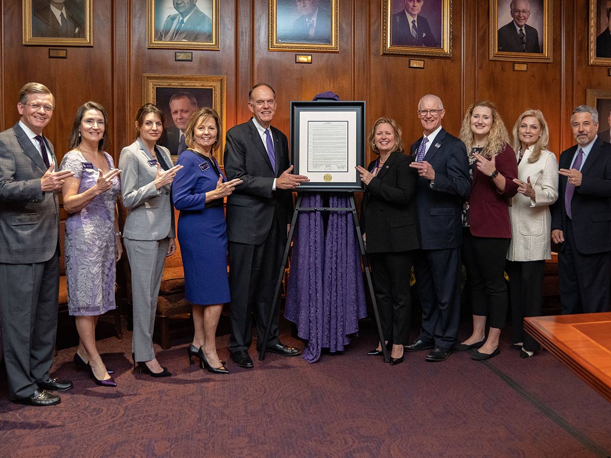 The Board of Regents and Westbrook show their axe 'em signs by the resolution that made Westbrook the 10th president of SFA. Regent David Alders wrote the resolution and read it at the board meeting. Pictured, from left, are Alders; Judy Larson Olson; Jennifer Wade Winston, board secretary; Brigettee Carnes Henderson; Westbrook; Karen G. Gantt, board chair; M. Thomas Mason, board vice chair; Paige Vadnais, student regent; Nancy C. Windham; and Robert A. Flores. Photo by Lizeth Rodriguez Santes