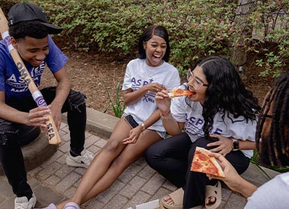Students eating pizza and laughing