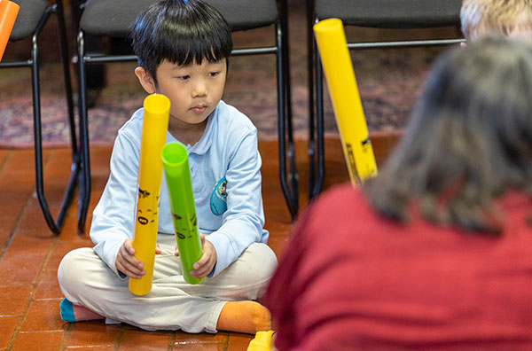 Child holding instrument and watching teacher