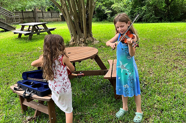 Two young students playing violin outside
