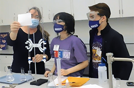 Professor working with students in chemistry lab