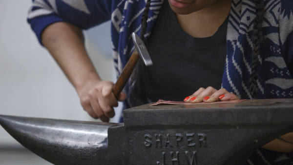 A student works with metals on an anvil