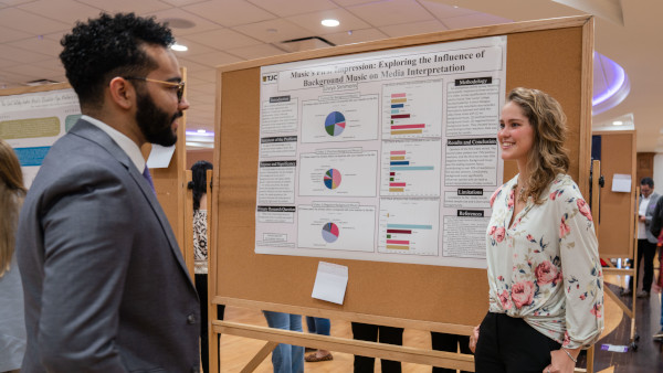 A student presenter shares her research during a poster session