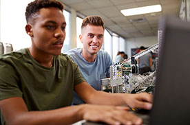 two young men working on computers in a lab