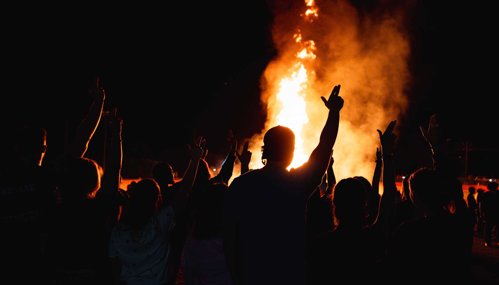 Students standing in front of homecoming bonfire with their Axes Up