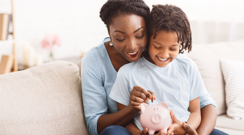 mother putting a quarter into piggy bank child is holding