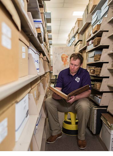 Archivist Kyle Ainsworth, pictured seated in the stacks of SFA's ETRC. Ainsworth catalogued runaway slave ads as part of the Texas Runaway Slave Project he started in 2015.