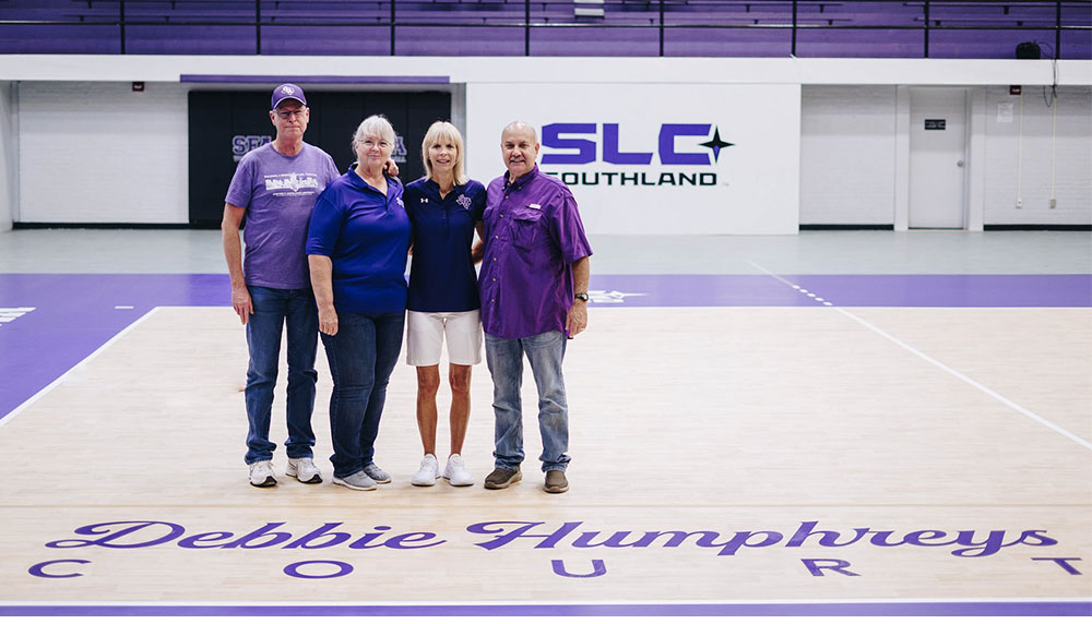  Debbie Humphreys, second from right, poses for a photo on the newly dubbed Debbie Humphreys Court with, from left, Alan and Kim Jones and Humphreys’ husband, Richard. The Joneses generously funded the new Taraflex court, the gold standard in collegiate volleyball surfaces, making SFA the only institution in the Southland Conference to boast such luxury.