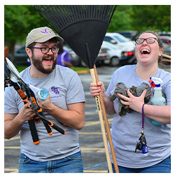 Students laughing while carrying gardening tools