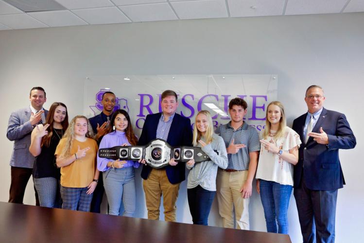 Drs. Tim Bisping and Jason Reese of the Nelson Rusche College of Business pose with the top eight ticket sellers of the Battle of the Piney Woods competition.