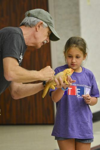 Stephen F. Austin State University alumnus K.C. Rudy of Wildlife on the Move gives Kayla Handy a closer look at a bearded dragon during his presentation to Little STEM Jacks