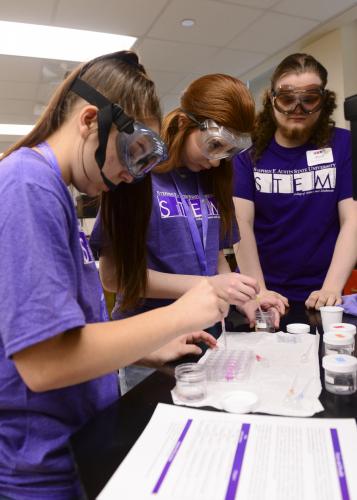 Students conduct an experiment simulating how chemists determine toxicity while Paul Rogers, SFA junior computer science major from Wells, assists.