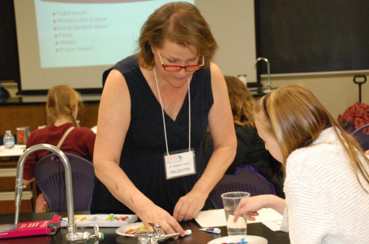 Dr. Maggie Leysath working with one of the students in her art education session