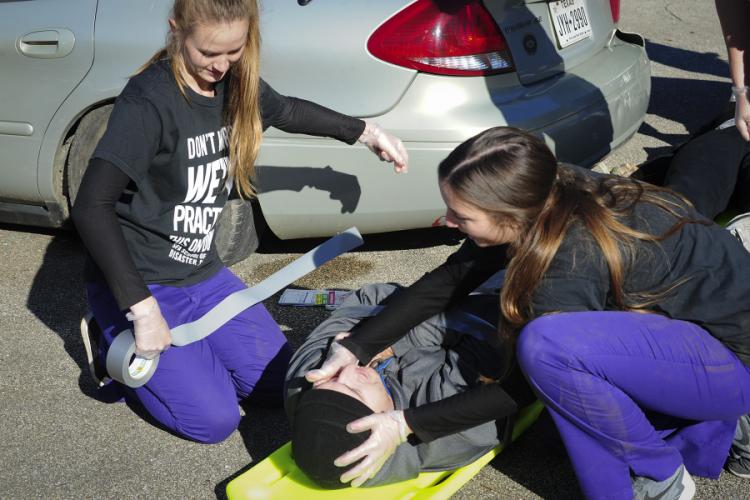 Senior nursing students enrolled in Stephen F. Austin State University’s DeWitt School of Nursing strap a patient to a backboard during a disaster simulation drill. 