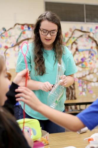 Carolyn Bugg, an elementary education and interdisciplinary studies major at Stephen F. Austin State University, helps students at Raguet Elementary School build an invention during the Novel Engineering project.