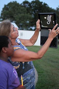 Utilizing an iPad and the Skyview app, Dr. Nola Schmidt, STEM Center curriculum coordinator, and Xavior Walker map out a constellation at the SFA Observatory. 