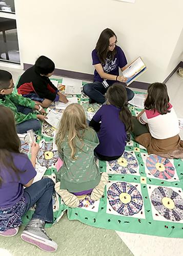 an SFA elementary education student reading to a group of Charter School students during the "We Need Diverse Books" event