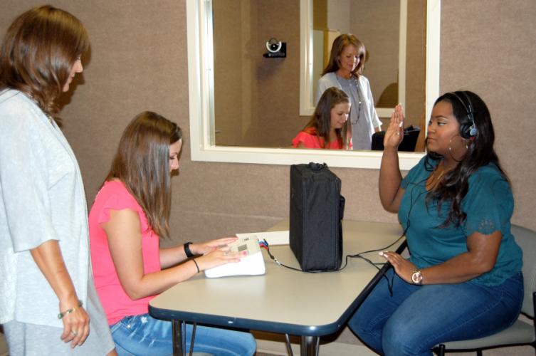 graduate students practice administering hearing screenings on each other in the Gwen and Ed Cole Audiology Lab 