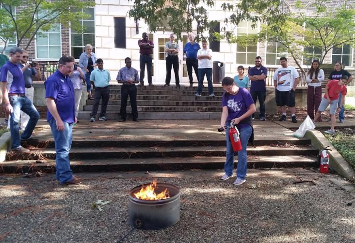 SFA Department of Chemistry and Biochemistry graduate student Amanda Raley took her turn extinguishing a fire as fellow graduate students look on. 