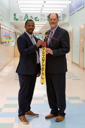 Gerald Fonzie, former assistant principal at Brooks-Quinn-Jones Elementary School in Nacogdoches, accepts the official BQJ principal banner from Tom Miller, who retired as principal this year. 