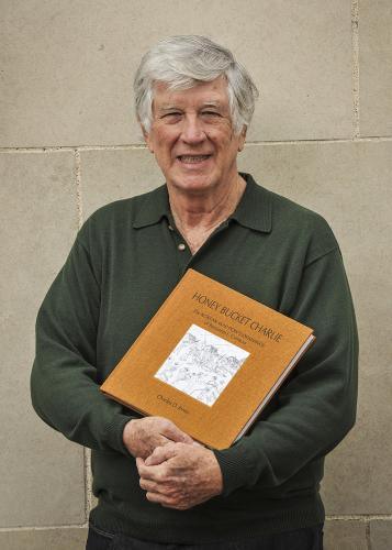 Charles D. Jones holds a copy of "Honey Bucket Charlie: The Korean War POW's Drawings of Benjamin L. Comeau"
