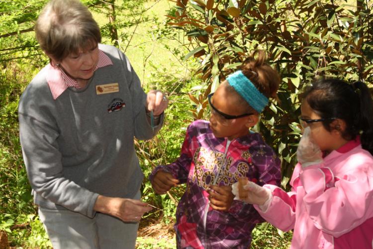 Marianne Young, SFA Gardens volunteer, demonstrates how to accurately test water quality to Nacogdoches ISD third graders