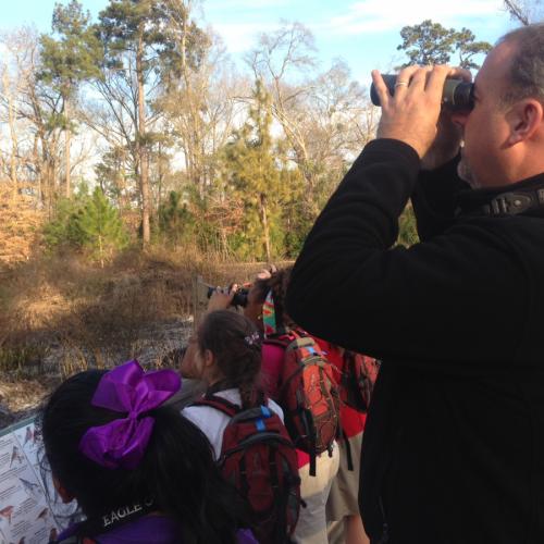 a photo of Cliff Shackelford looks for birds with young bird watchers