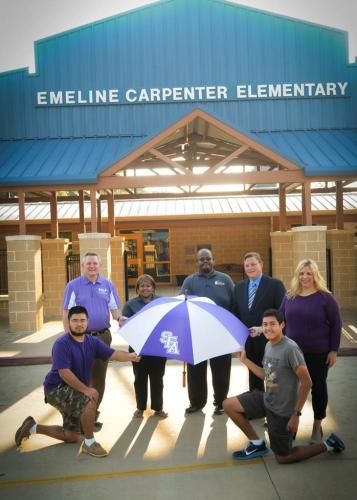 SFA student affairs staff members and Generation Jacks Program members pose with one of the donated umbrellas infront of Emeline Carpenter Elementary School in Nacogodoches