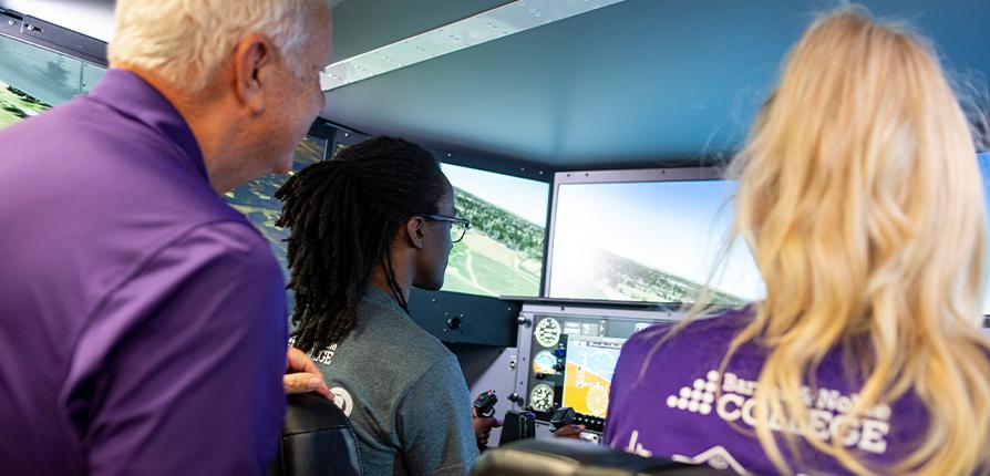 Instructor and two students with flight simulator