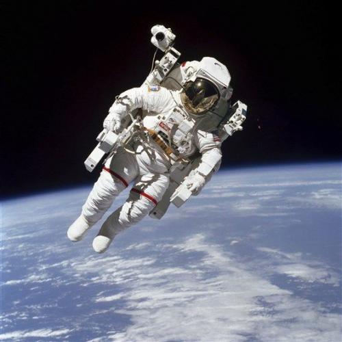 photo of Captain Bruce McCandless II with a jet-powered backpack in space above the Earth