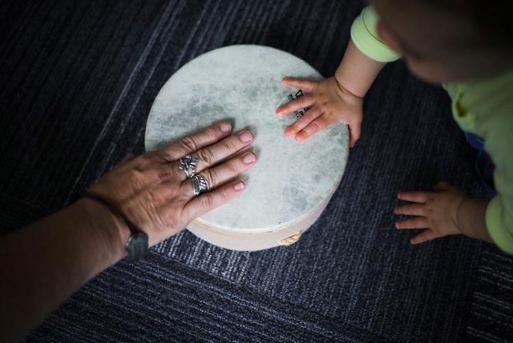the hand of an adult and the hand of a young child laying on top of opposite sides of a tamborine
