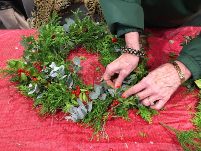 woman making a wreath with evergreens