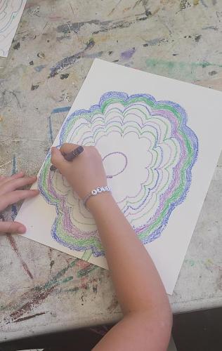 A student creates art with crayons and paper