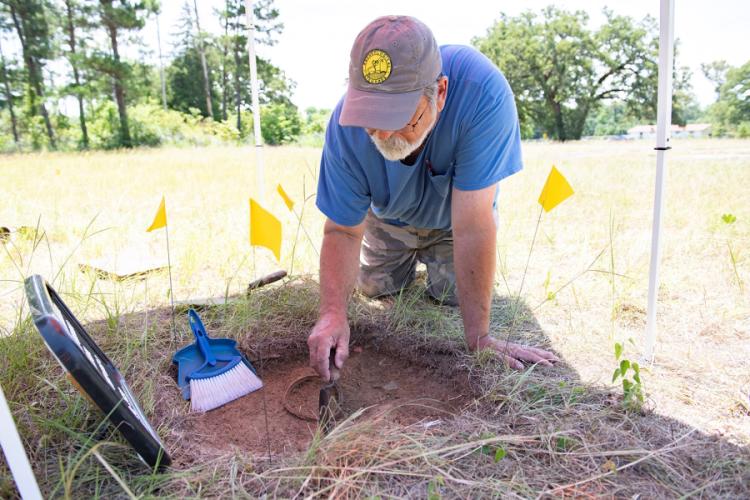 volunteer Keith Stephens uses tools to inspect the initial dig, or test unit