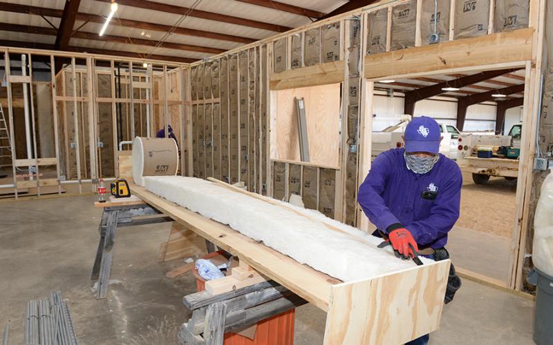 SFA employee cutting insulation for a building