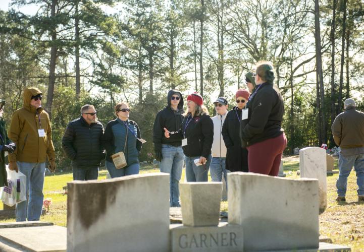 Dr. Perky Beisel talks to a group of participants about a gravestone at the Sand Hill Cemetery.