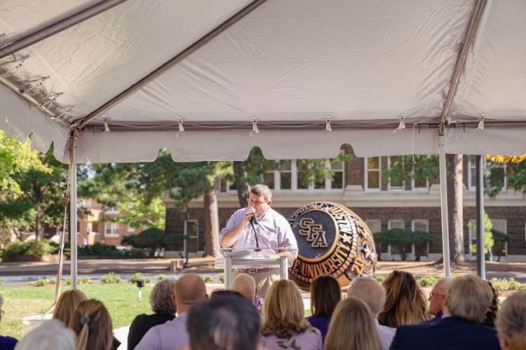 Craig Turnage, executive director of Stephen F. Austin State University’s Alumni Association, addresses attendees during the Centennial Ring Plaza dedication event Monday.