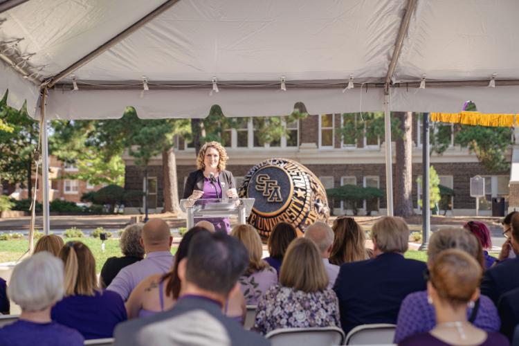 Erika Tolar, president of Stephen F. Austin State University’s Alumni Association, addresses attendees during the Centennial Ring Plaza dedication event Monday.