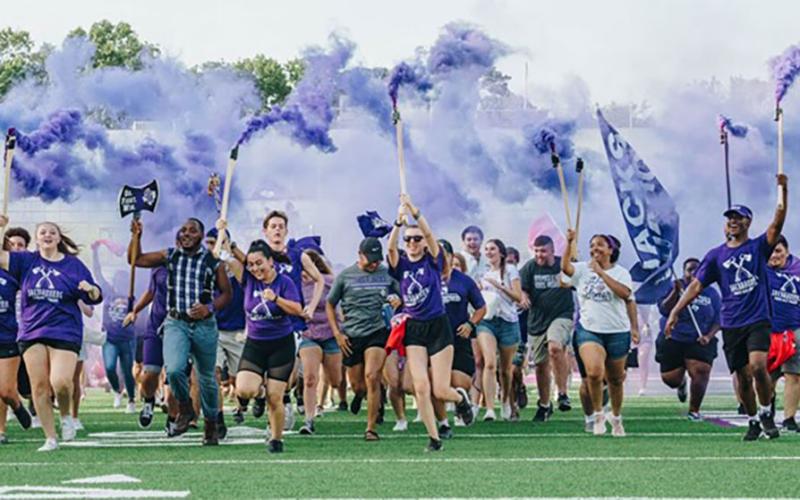 Students running on the field before an SFA football game